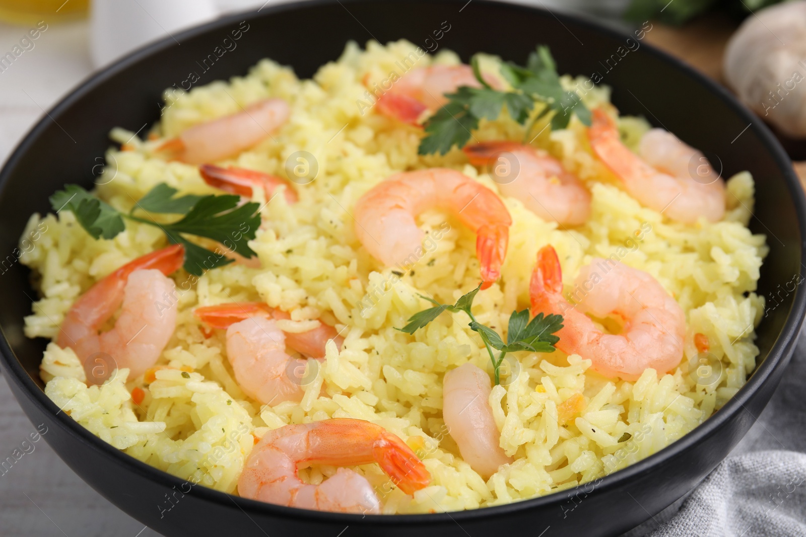 Photo of Delicious risotto with shrimps and parsley in bowl on table, closeup