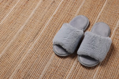 Photo of Soft fluffy grey slippers on carpet, space for text