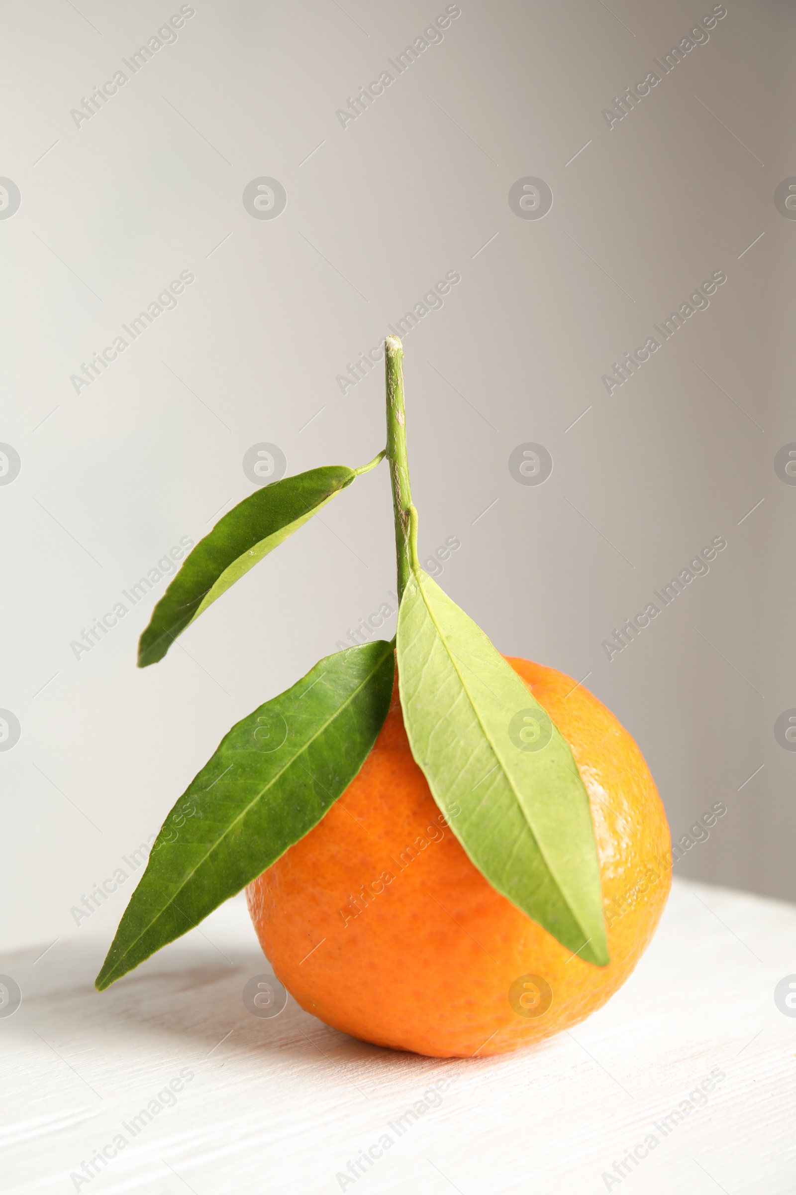 Photo of Tasty ripe tangerine with leaves on table