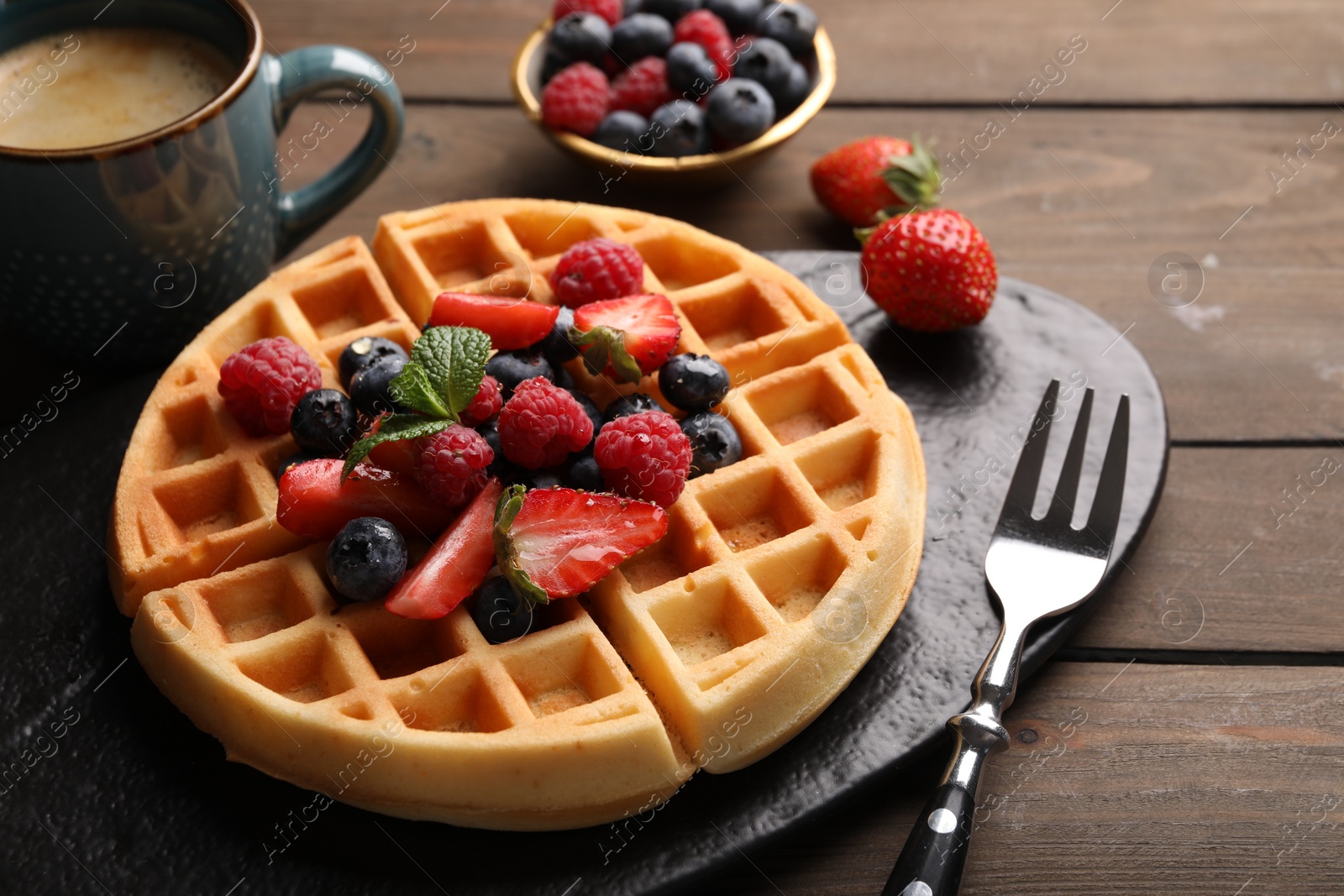 Photo of Tasty Belgian waffle with fresh berries served on wooden table, closeup