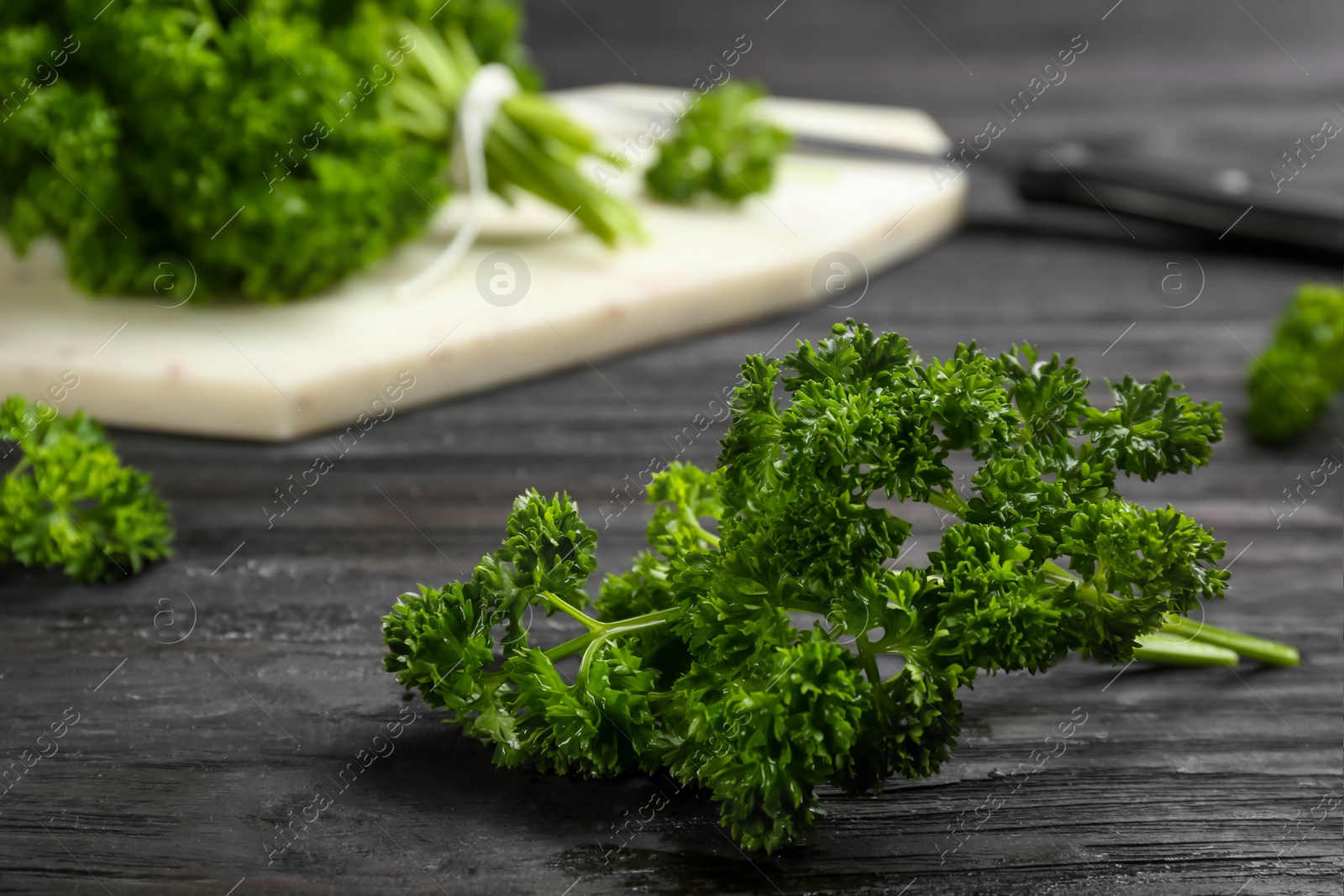 Photo of Fresh curly parsley on black wooden table