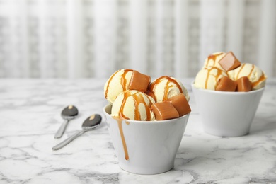 Photo of Delicious ice cream with caramel and sauce served on marble table