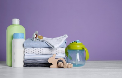 Children's accessories and stack of clothes on white wooden table