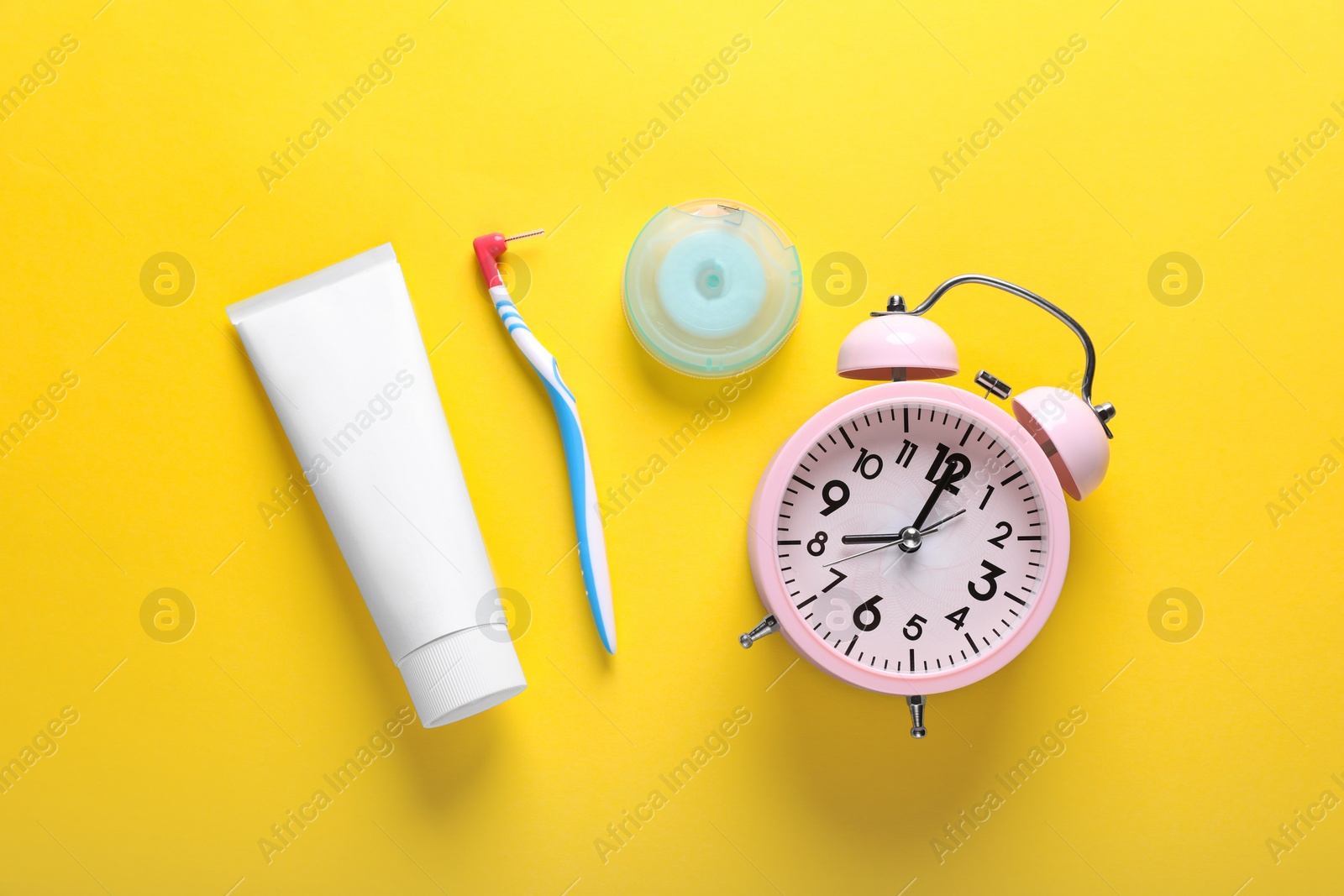 Photo of Container with dental floss, toothpaste and toothbrush on yellow background, flat lay
