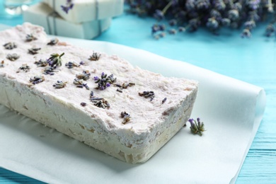 Photo of Hand made soap bar with lavender flowers on light blue wooden table, closeup