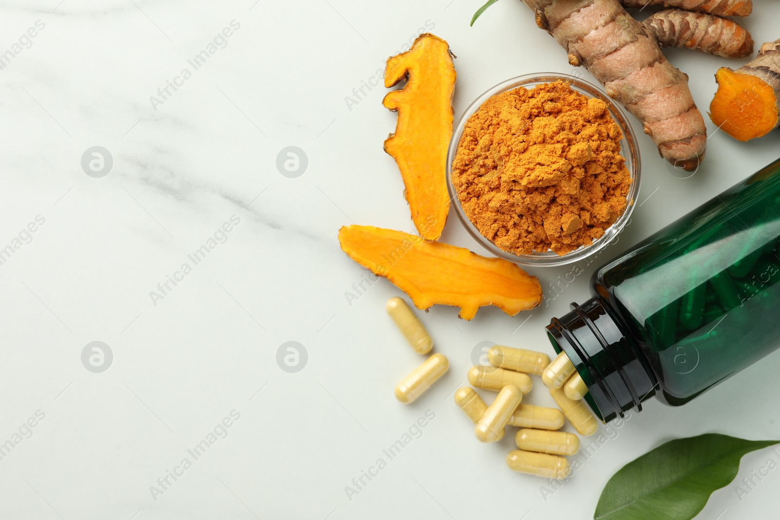 Photo of Aromatic turmeric powder, pills and raw roots on white marble table, flat lay. Space for text