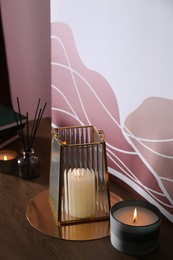 Burning scented candles on wooden table indoors