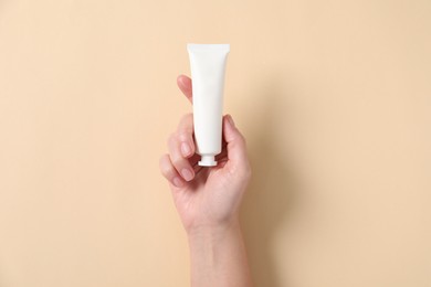 Photo of Woman with tube of hand cream on beige background, top view