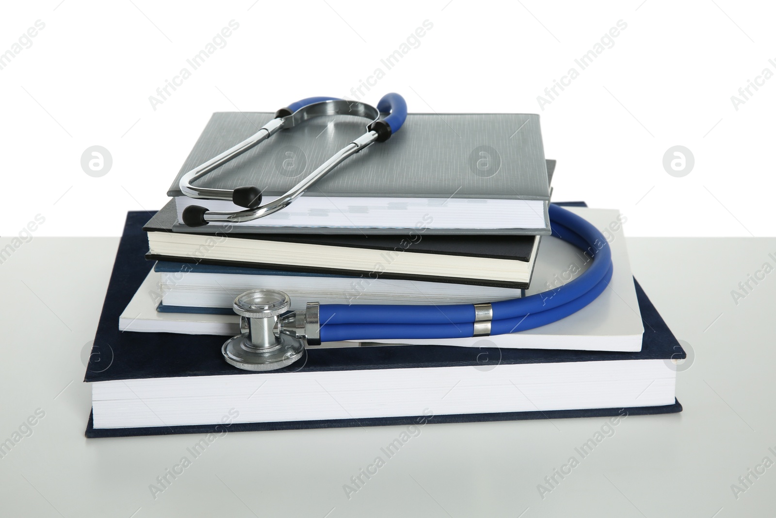 Photo of Stethoscope and stack of books isolated on white