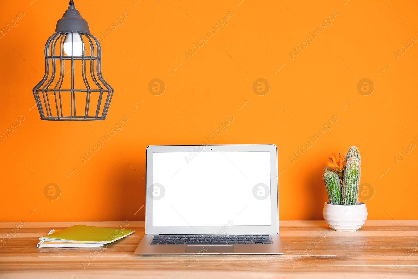 Photo of Modern laptop monitor on table against color wall. Mock up with space for text