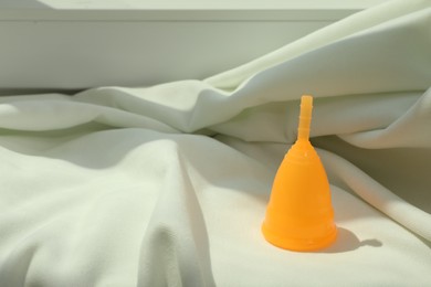 Menstrual cup on light fabric. Space for text
