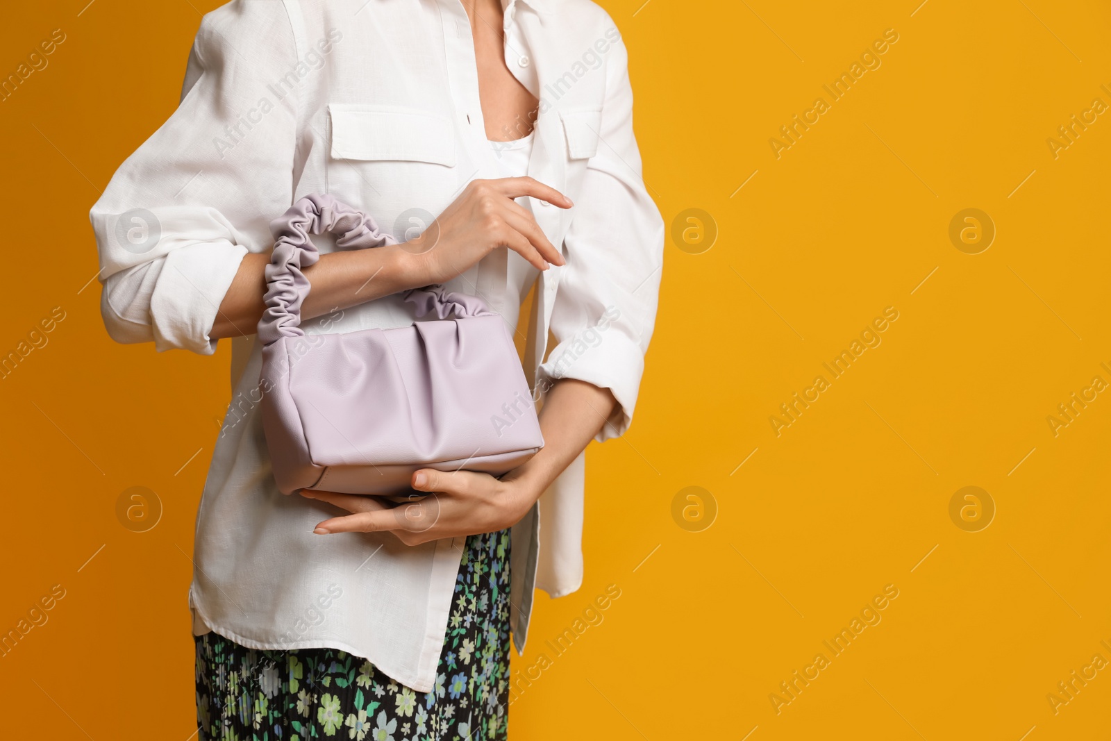 Photo of Stylish woman with trendy baguette bag on yellow background, closeup. Space for text