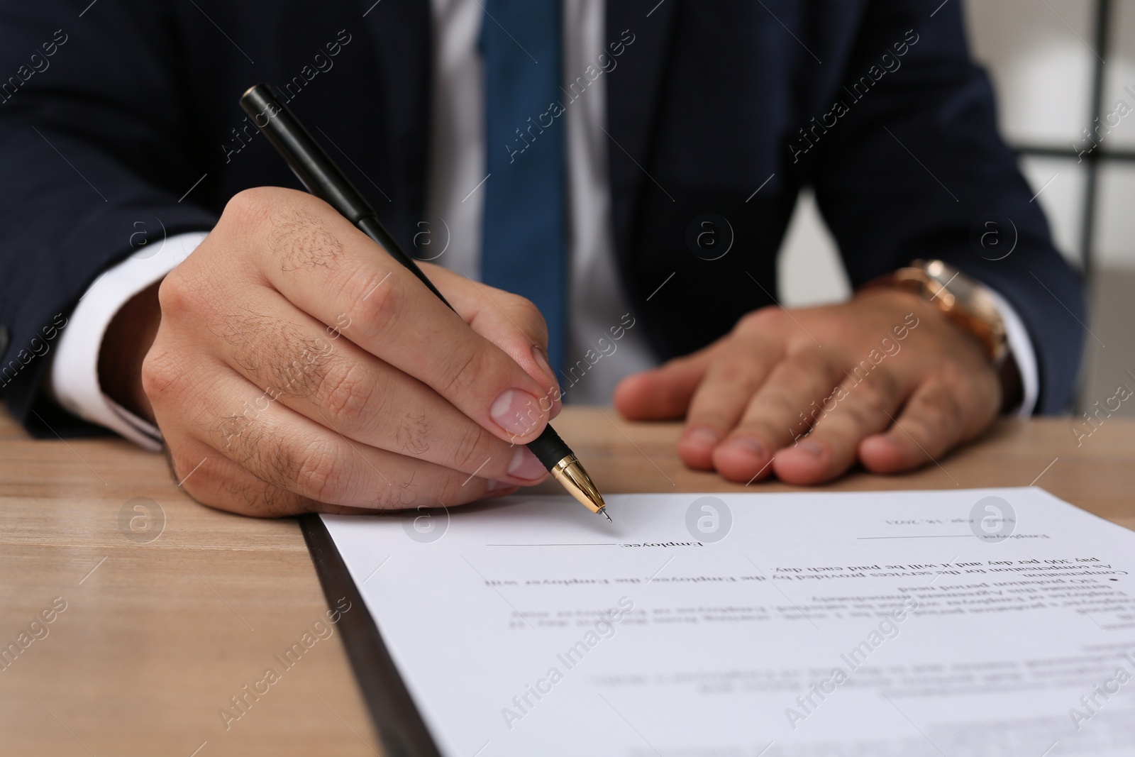 Photo of Businessman signing contract at wooden table indoors, closeup