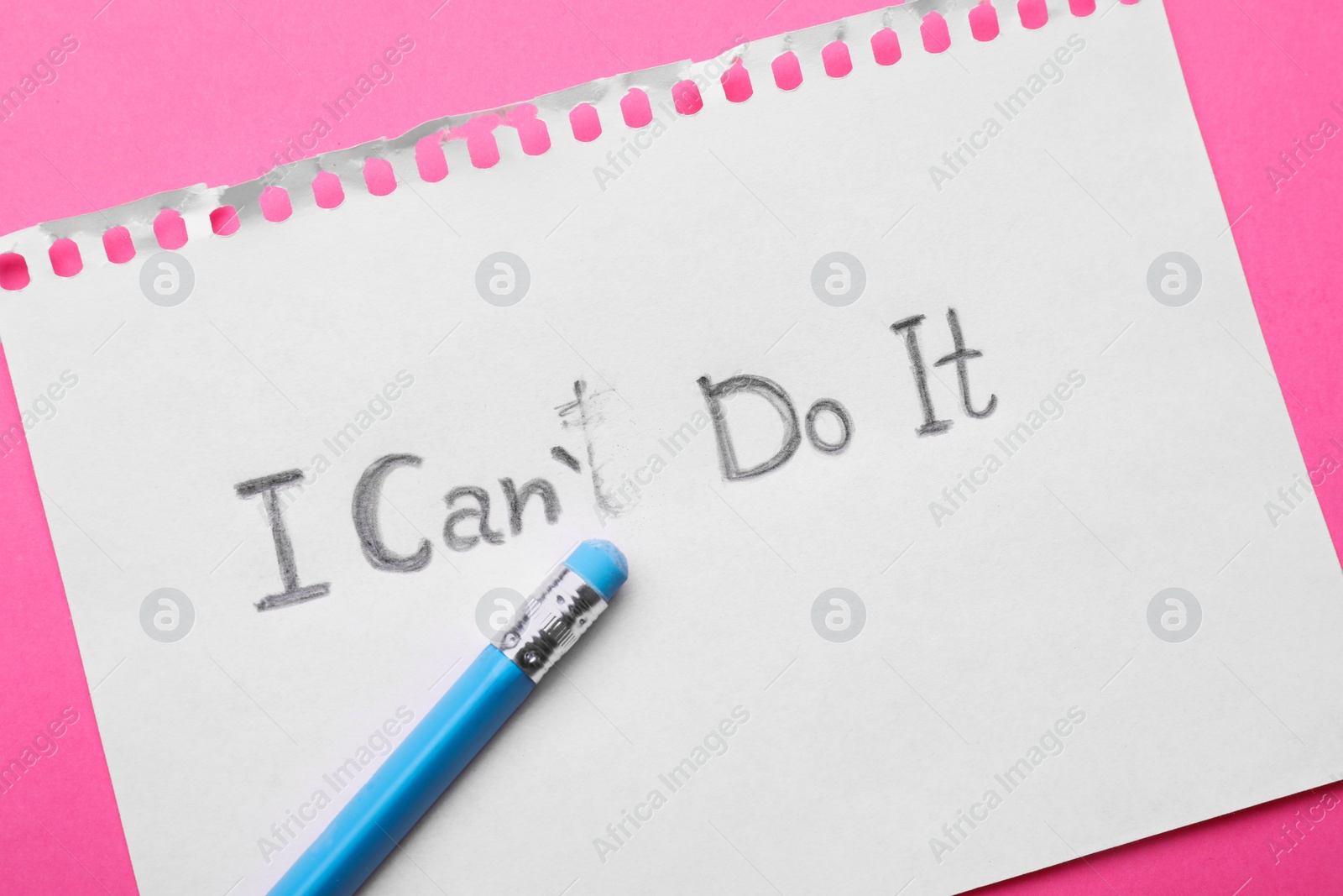 Photo of Motivation concept. Paper with changed phrase from I Can't Do It into I Can Do It by erasing letter T on pink background, top view