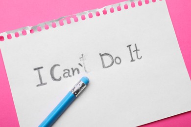 Photo of Motivation concept. Paper with changed phrase from I Can't Do It into I Can Do It by erasing letter T on pink background, top view