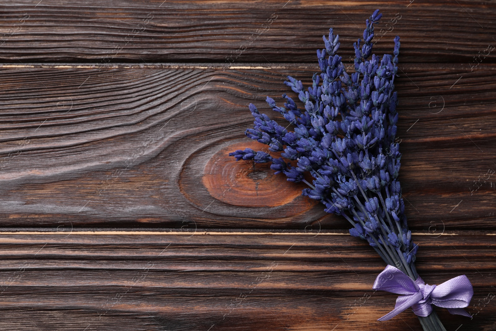 Photo of Bouquet of beautiful preserved lavender flowers on wooden table, top view. Space for text