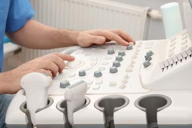 Photo of Sonographer operating modern ultrasound machine in clinic, closeup
