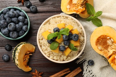 Photo of Flat lay composition with bowl of tasty quinoa porridge, pumpkin and blueberries on wooden table