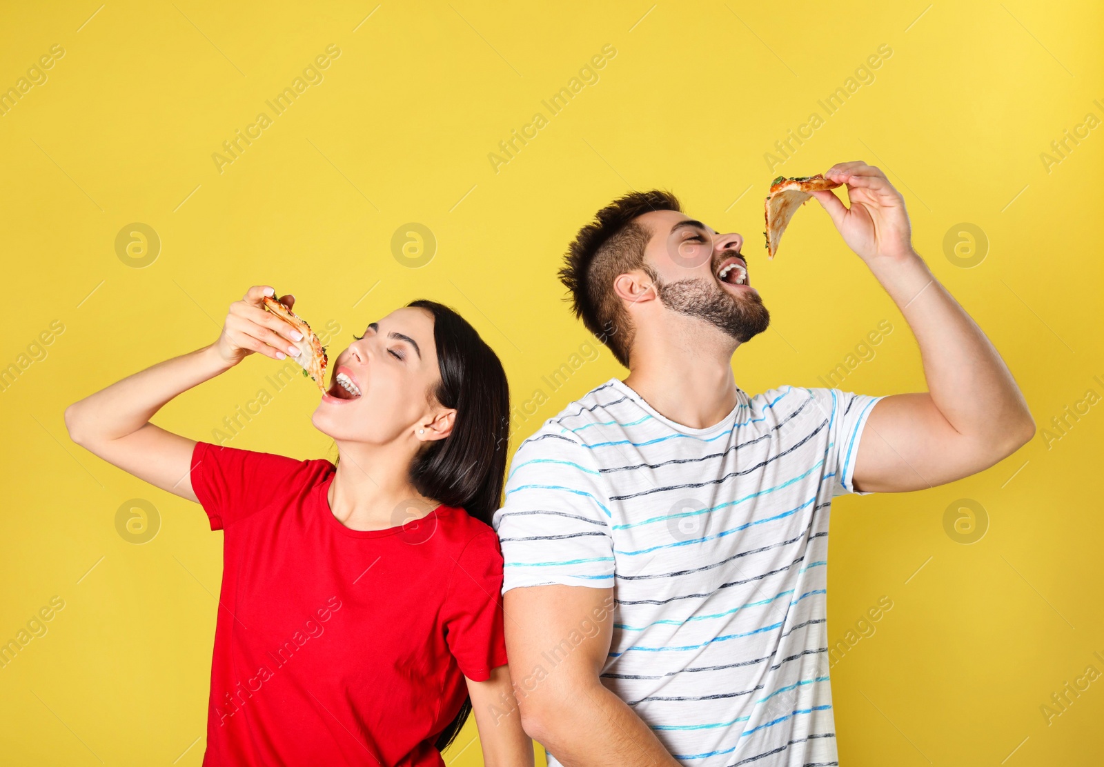 Photo of Young couple eating pizza on yellow background