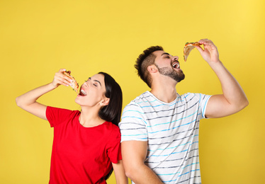 Photo of Young couple eating pizza on yellow background