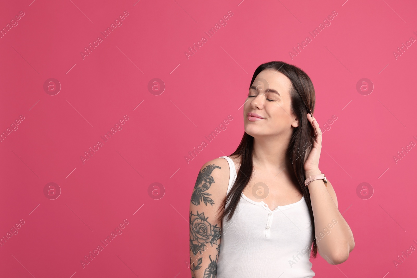 Photo of Beautiful woman with tattoos on arm against pink background. Space for text