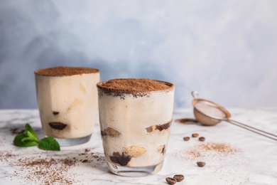 Photo of Two glasses of tiramisu cake on table against color background, space for text