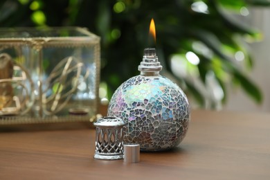 Photo of Burning catalytic purifying lamp on wooden table. Interior element