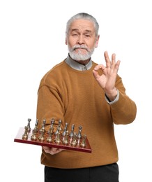 Man with chessboard and game pieces showing OK gesture on white background