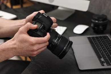 Photo of Photographer holding camera at dark table, closeup