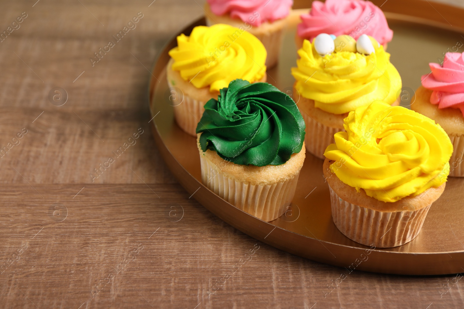 Photo of Delicious cupcakes with bright cream on wooden table. Space for text