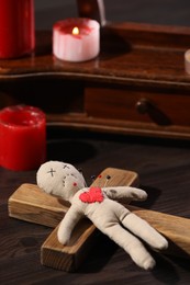 Photo of Voodoo doll with pins in heart and ceremonial items on wooden table