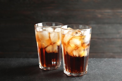 Photo of Glasses of refreshing cola with ice cubes on table