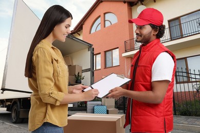 Image of Courier delivery. Woman signing order receipt outdoors