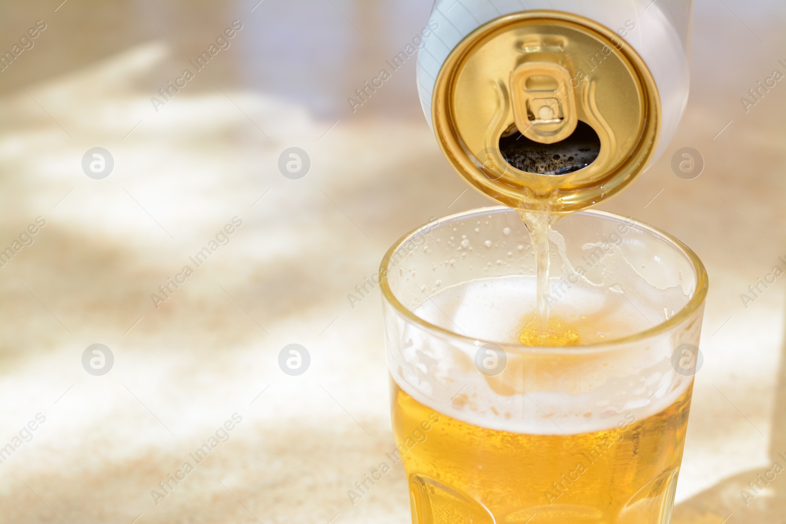 Photo of Pouring beer from can into glass on table, closeup. Space for text