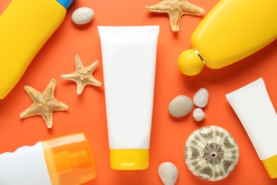 Photo of Suntan products and seashells on orange background, flat lay