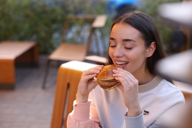 Photo of Lviv, Ukraine - September 26, 2023: Woman eating McDonald's burger outdoors, space for text