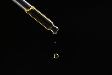 Photo of Dripping tincture from pipette on black background, closeup. Space for text