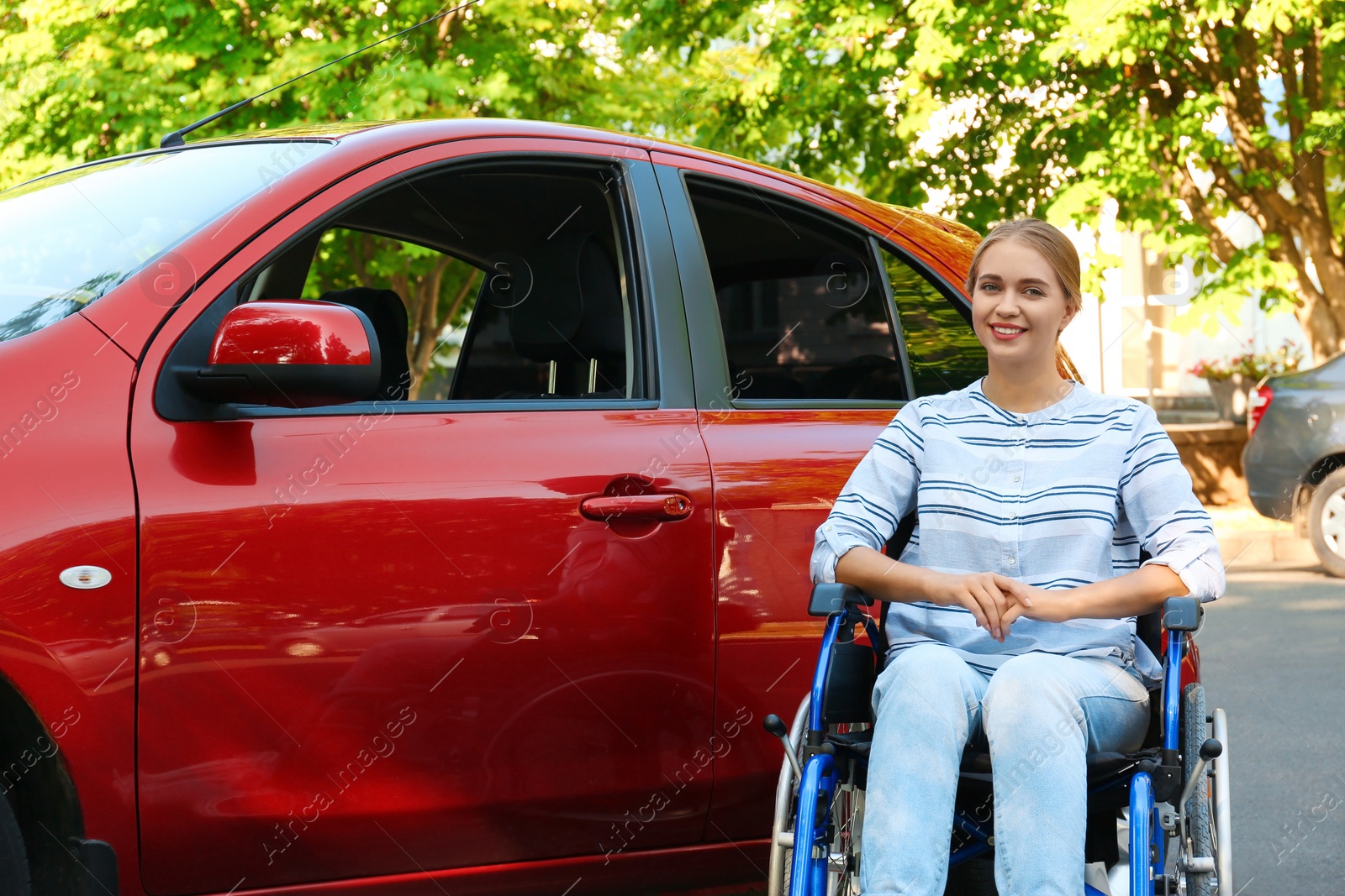 Photo of Young woman in wheelchair near car outdoors