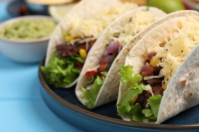 Photo of Delicious tacos with meat and vegetables on light blue table, closeup