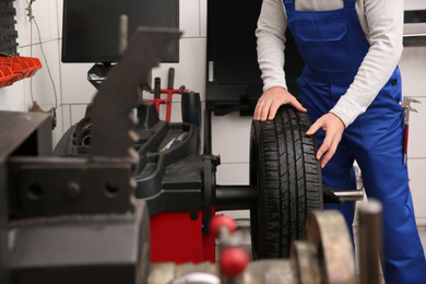 Photo of Mechanic working with wheel balancing machine at tire service, closeup
