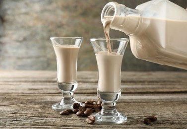 Photo of Pouring coffee cream liqueur into glass at wooden table, closeup