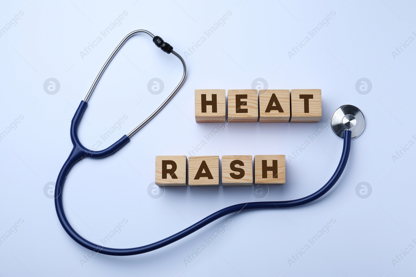 Photo of Wooden cubes with words Heat Rash and stethoscope on white background, top view