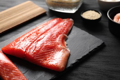 Photo of Fresh salmon for sushi on black wooden table, closeup