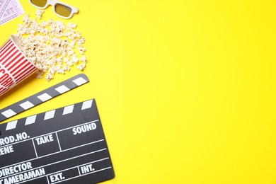 Flat lay composition with clapperboard and popcorn on yellow background, space for text