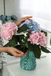 Photo of Woman with beautiful hortensia flowers in kitchen, closeup