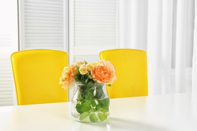 Vase with blooming flowers on table indoors