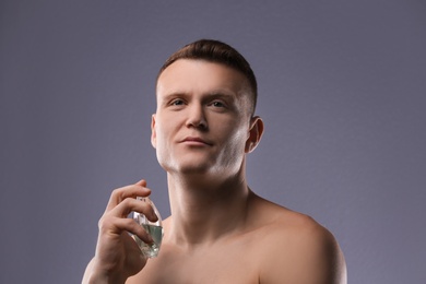 Photo of Handsome man using perfume on grey background