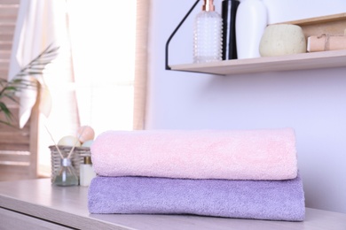 Stack of fresh towels on table in bathroom