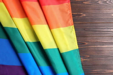 Bright rainbow gay flag on wooden background, top view with space for text. LGBT community