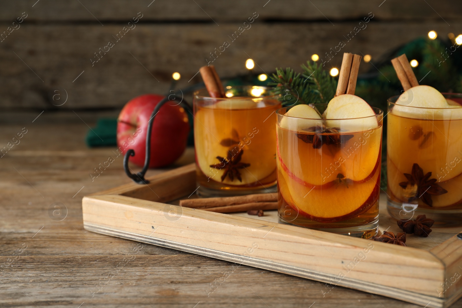 Photo of Hot mulled cider on wooden table, space for text